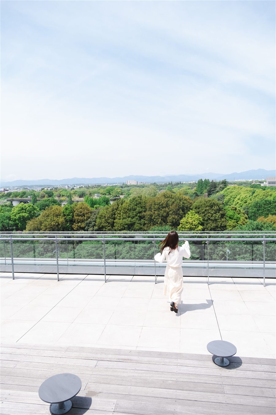 広い空と緑を眺める、白い服のまいさんの後ろ姿